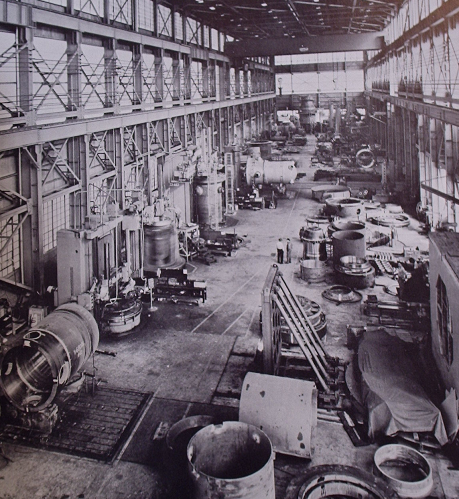 Reactor pressure vessel fabrication shop, Combustion Engineering, Inc., 1958.  Various vessels for commercial and military applications are seen in fabrication.  Note the vessel being spun on a machining table along the left wall, blurring the image.  This image can immediately be identified as early as the vessels are still small (later ones for 1000 MWe commercial plants were tall enough to stretch almost across the entire hall when laid sideways) and because at least one vessel is visible with coolant penetrations in its lower head, i.e. below the reactor core when installed.  This was later considered potentially unsafe as a rupture could drain the core quickly, and all large penetrations were then kept above actual core level.